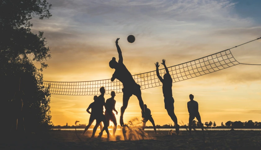 volleyball players play against the setting sun