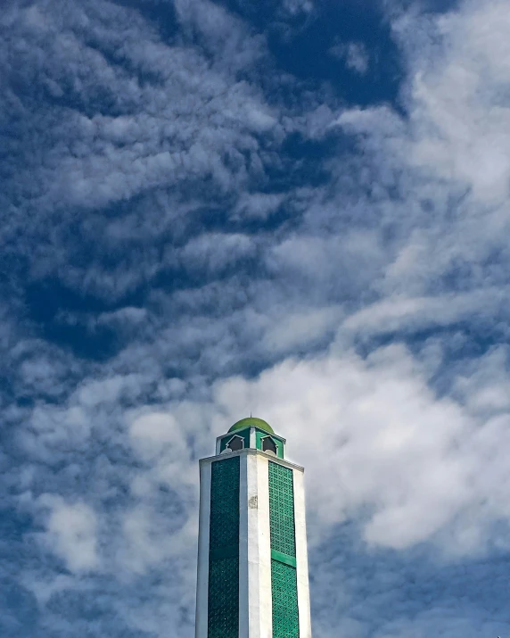 the top of a tall clock tower under a cloudy blue sky