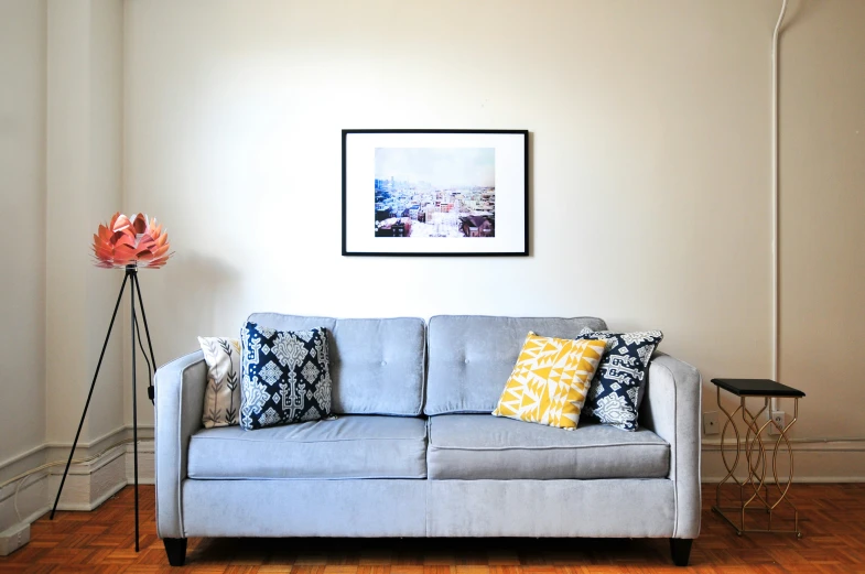 a grey couch in a corner with colorful pillows on it