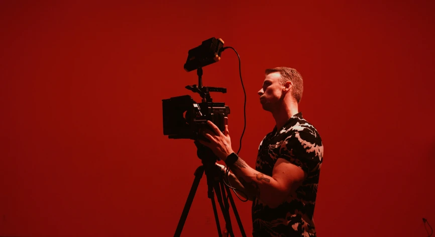 a man is recording his music on a red background