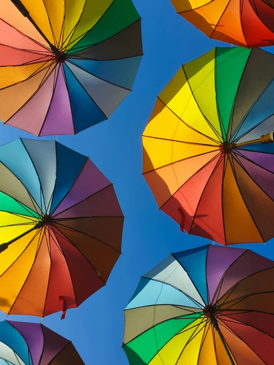 many colorful umbrellas are standing out against a blue sky