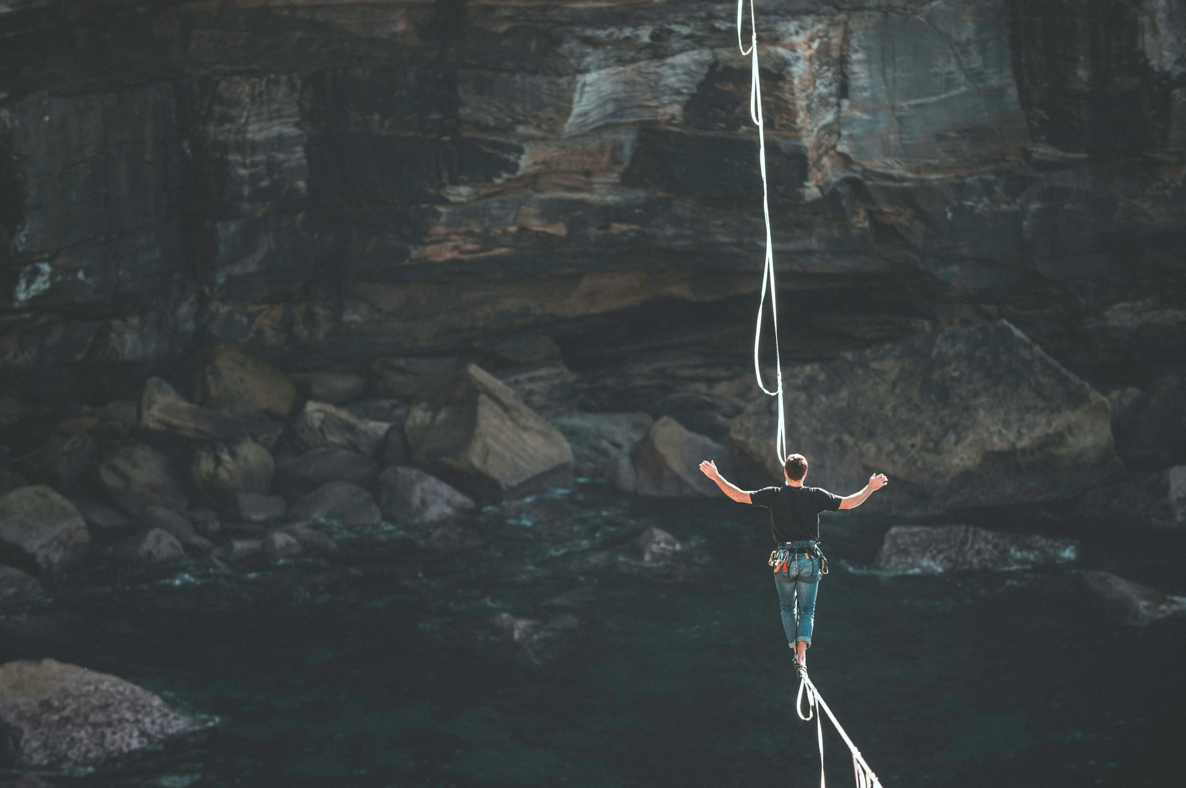 a man hanging from a rope above water in the desert