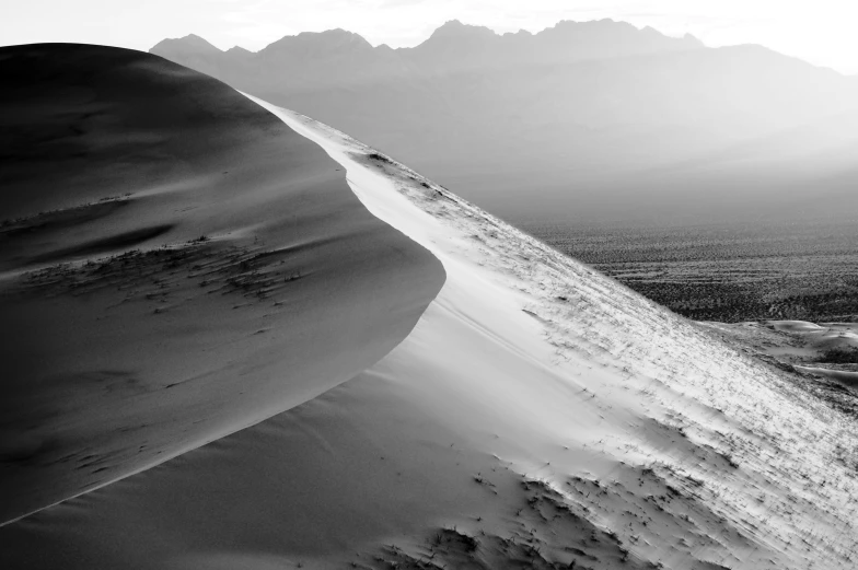 the sun is setting on the side of a large dune