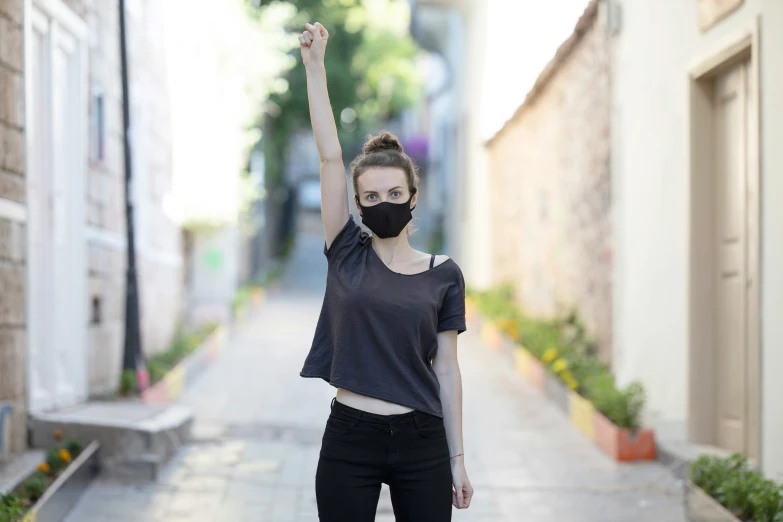 a person in black shirt and mask on street with buildings