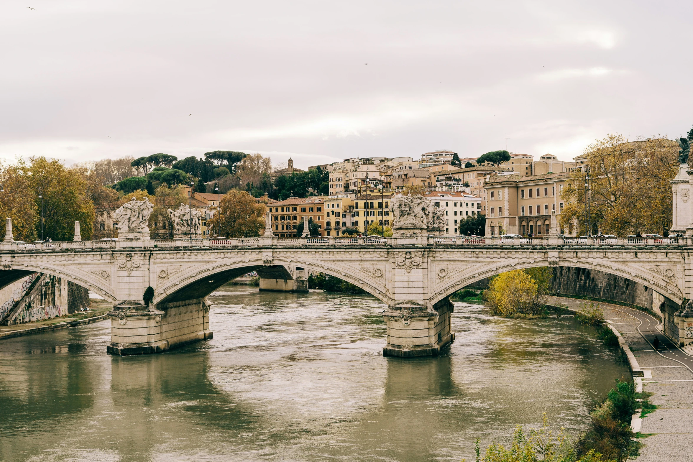 a stone bridge across a river in front of many buildings