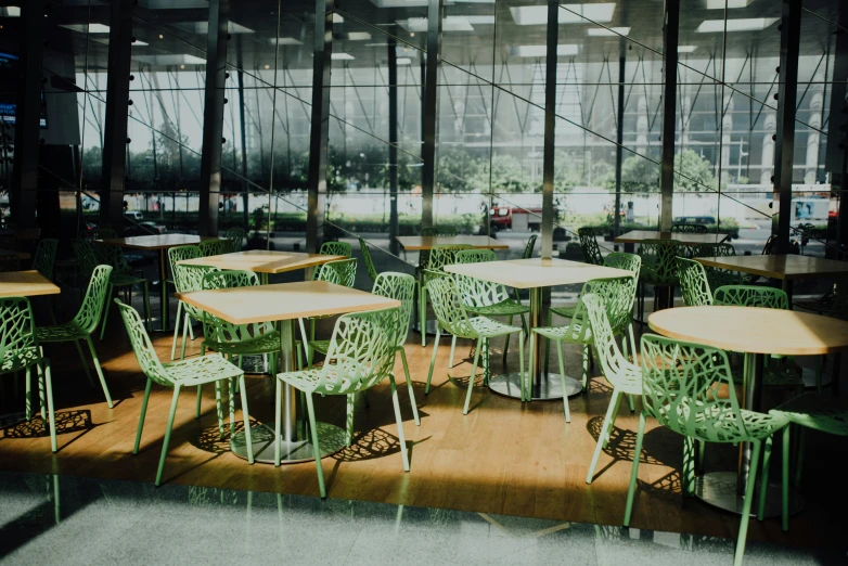 many green chairs are around the round wooden tables