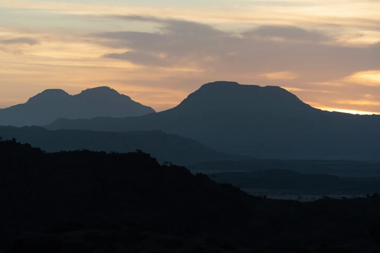 the silhouette of several mountains against a cloudy sky