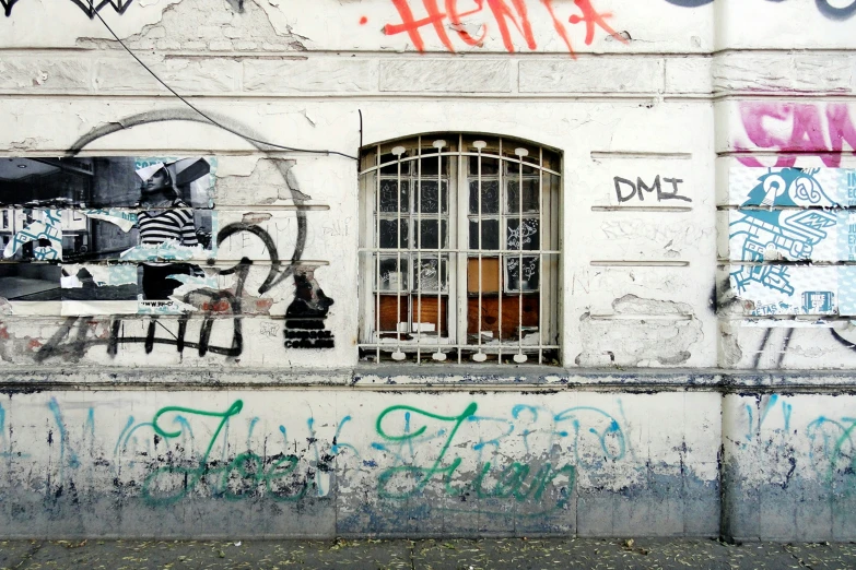 a wall with graffiti on it has a window and some words written in it