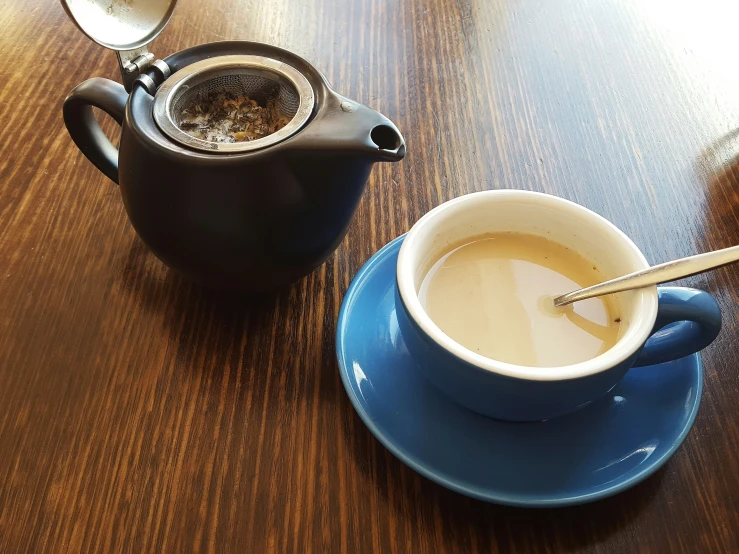 a coffee pot and teacup sitting on a table