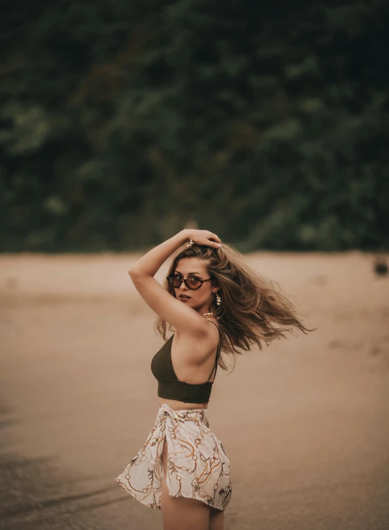 woman with long brown hair on beach wearing black top