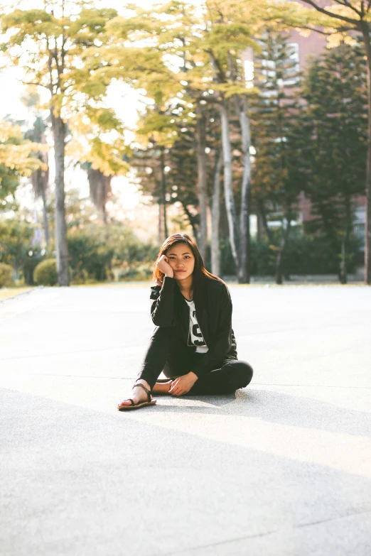 a woman kneeling on the ground in front of trees