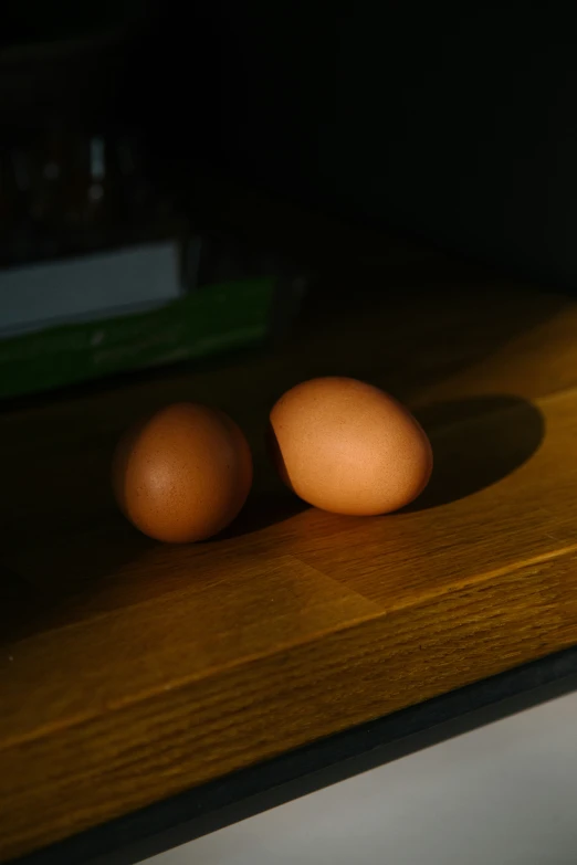 two eggs sit on a table in the sun