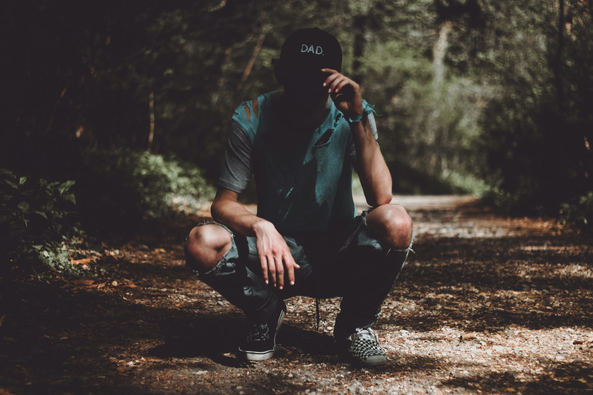 a man squatting down outside with his hands in his pockets