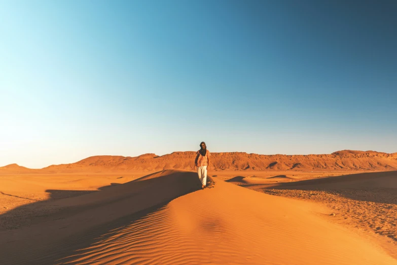 a man walking on top of a sandy desert