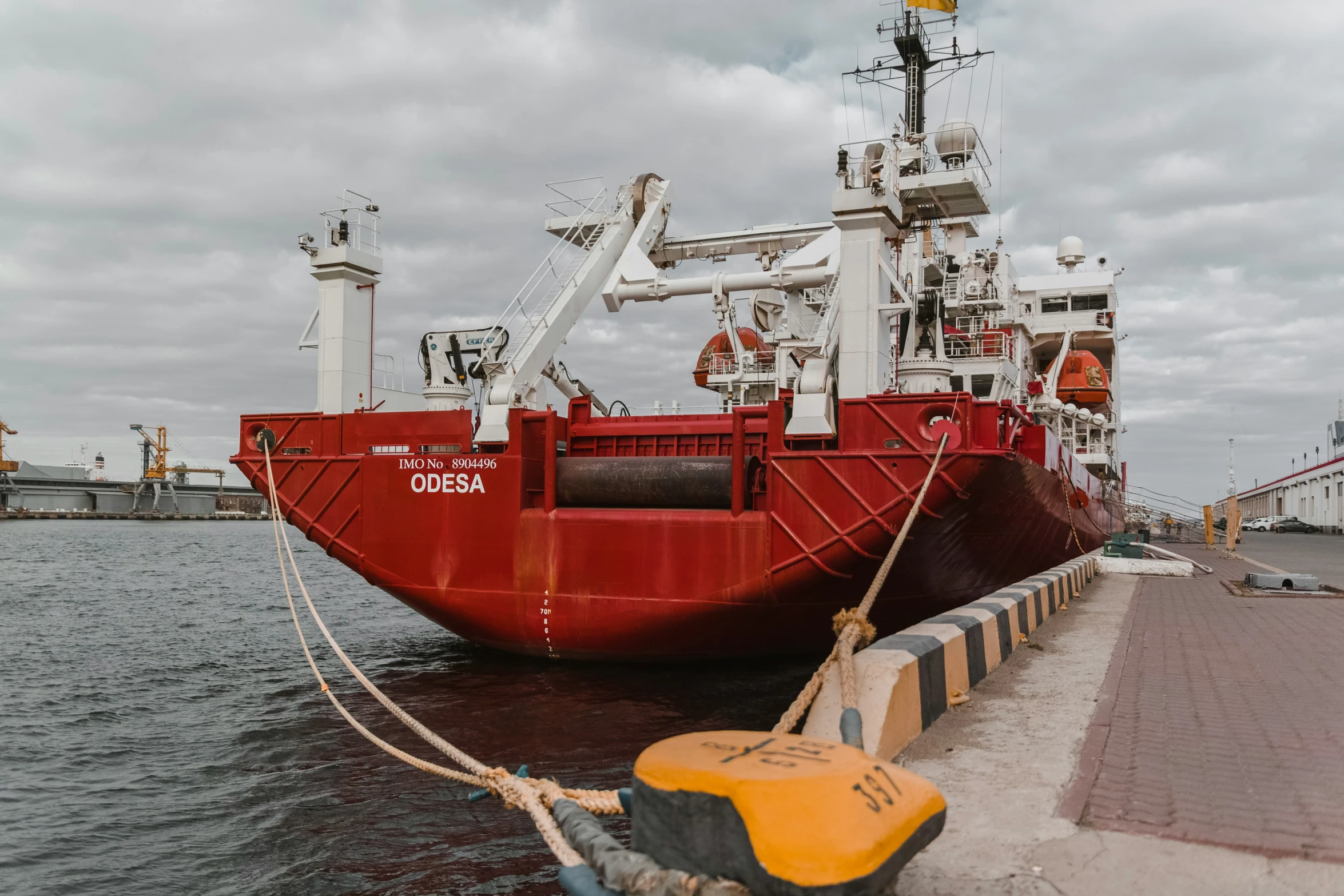 large red and white cargo ship docked at port