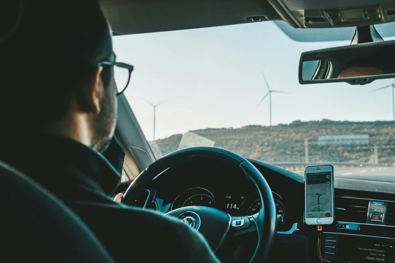 a driver sits in his vehicle and watches traffic on a sunny day