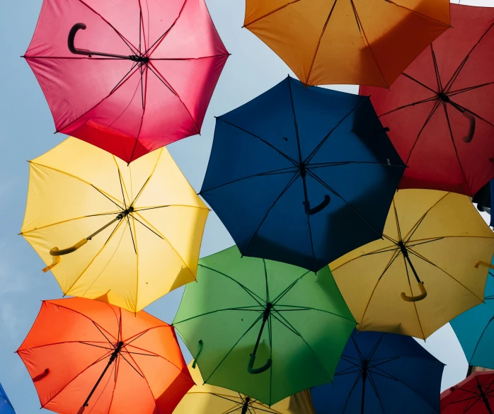 a large group of colorful umbrellas being flown together