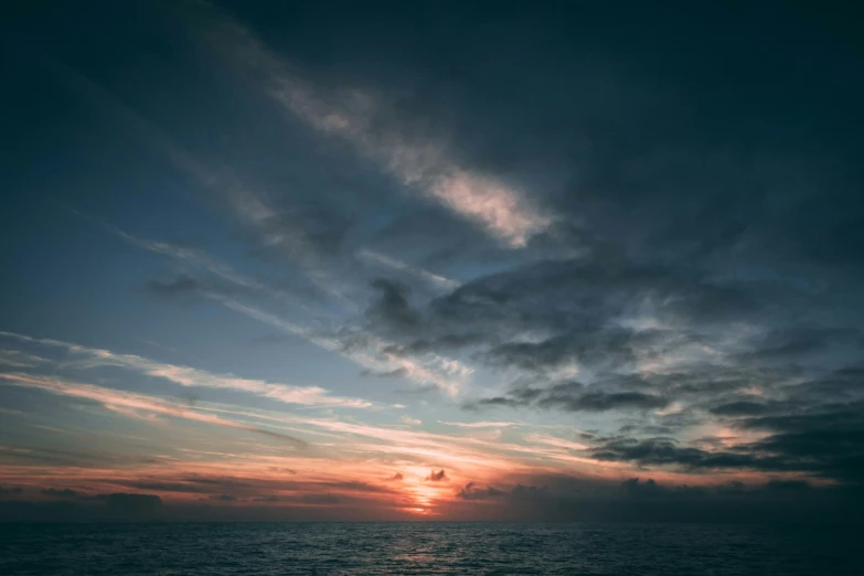 the sun is rising over the ocean with clouds