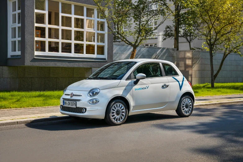 a small white car driving down a street next to a building