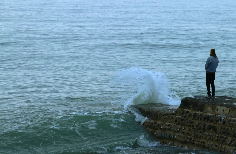 a person stands on a cliff overlooking the ocean