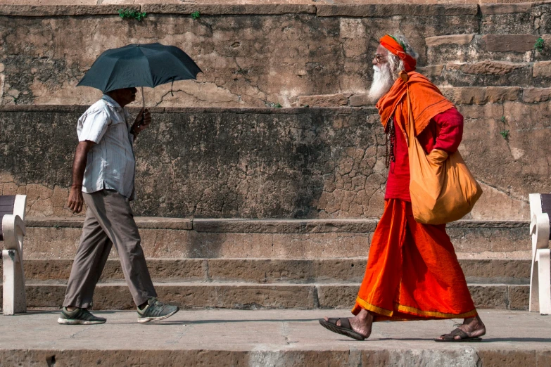 a bearded man walking down the street holding an umbrella