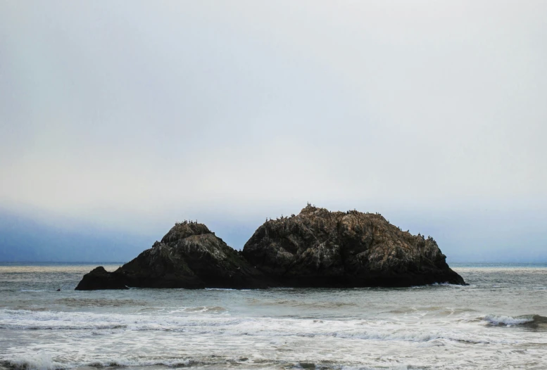 two rocks sitting in the water at the beach