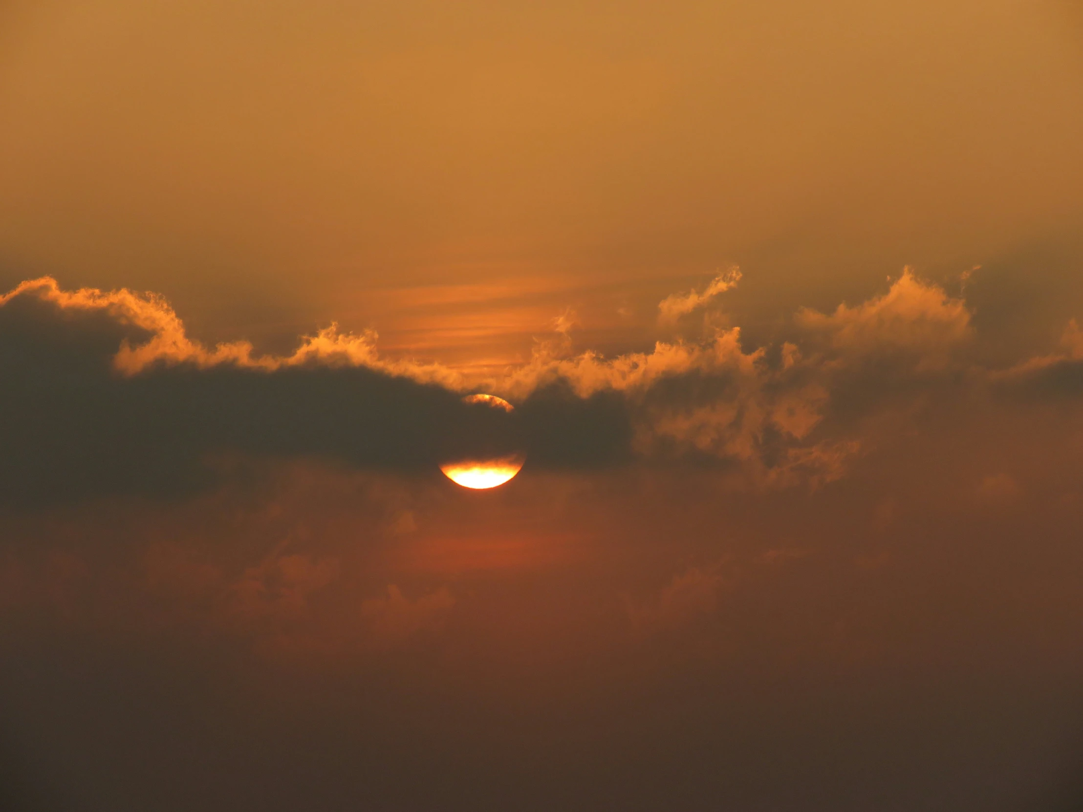 sun setting behind dark clouds with red and yellow hues