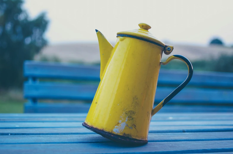 an empty yellow teapot sitting on a wooden table