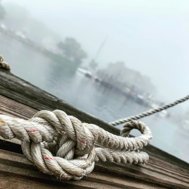 a rope tied up near a pier with boats in the background