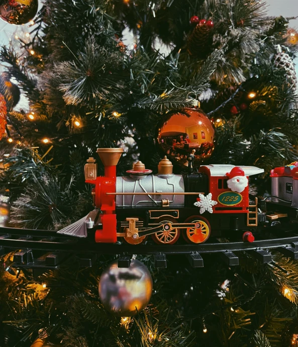 a christmas tree with ornaments and a small train