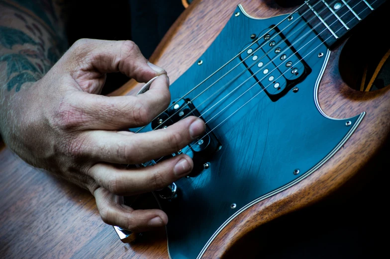 a person holding a black and wood guitar