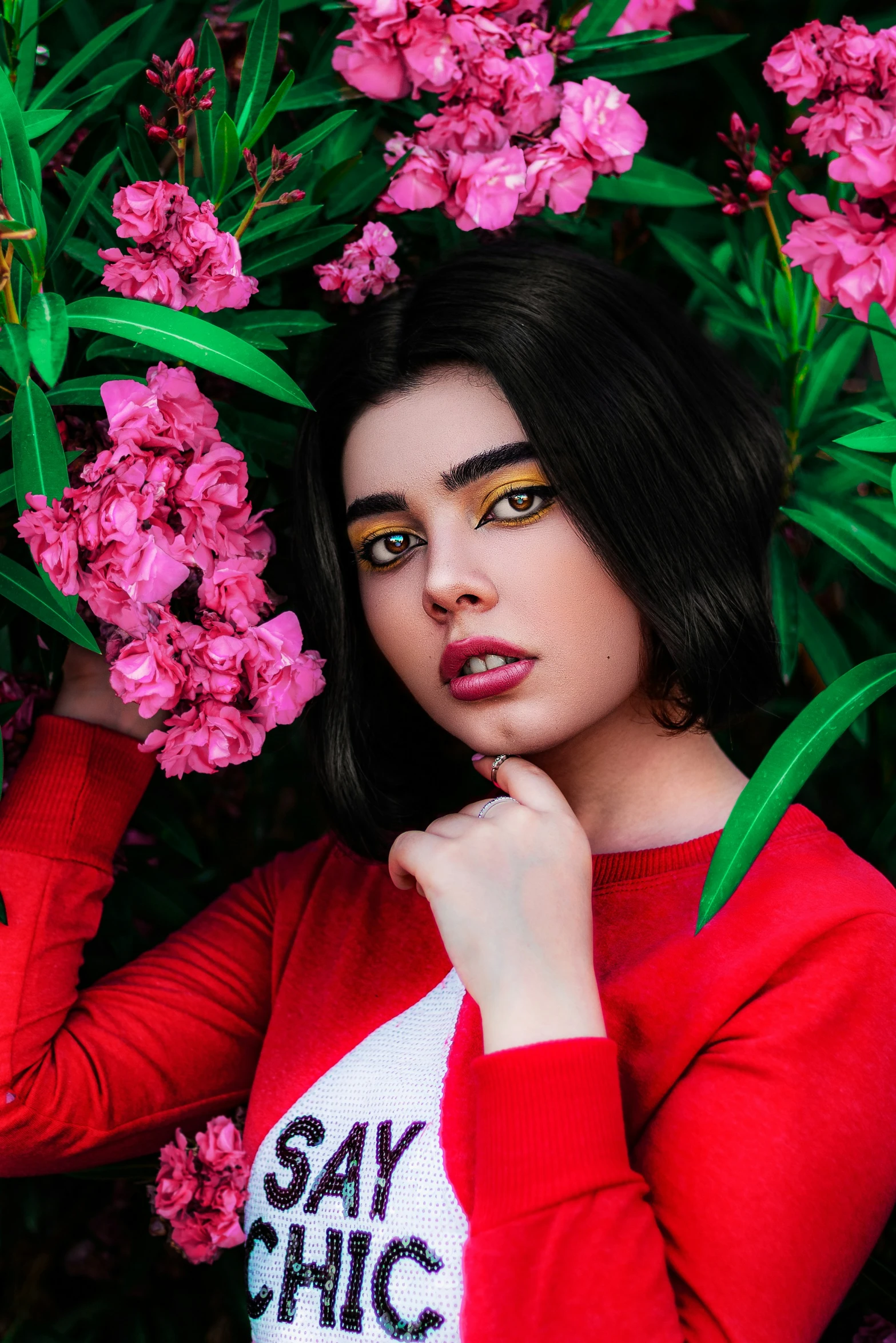 a beautiful young woman posing in front of pink flowers