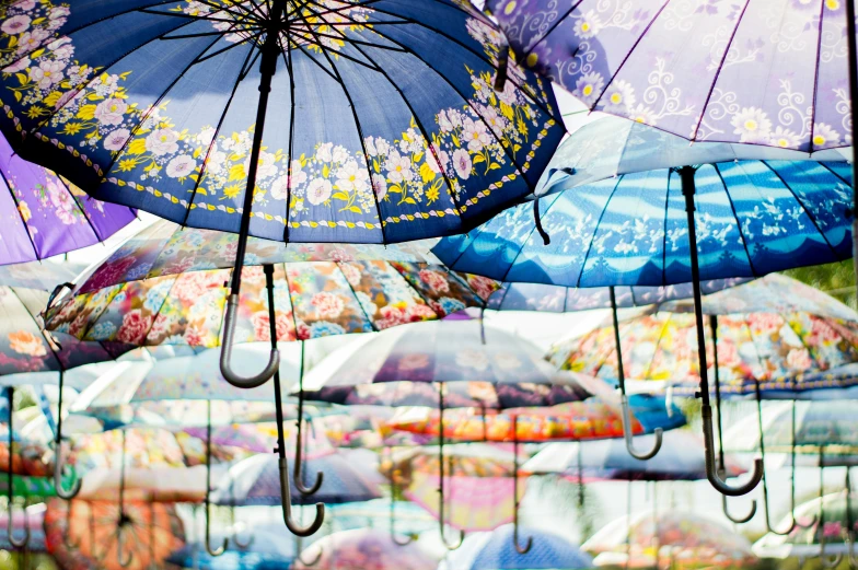 several open umbrellas hanging in front of a lot of other umbrellas