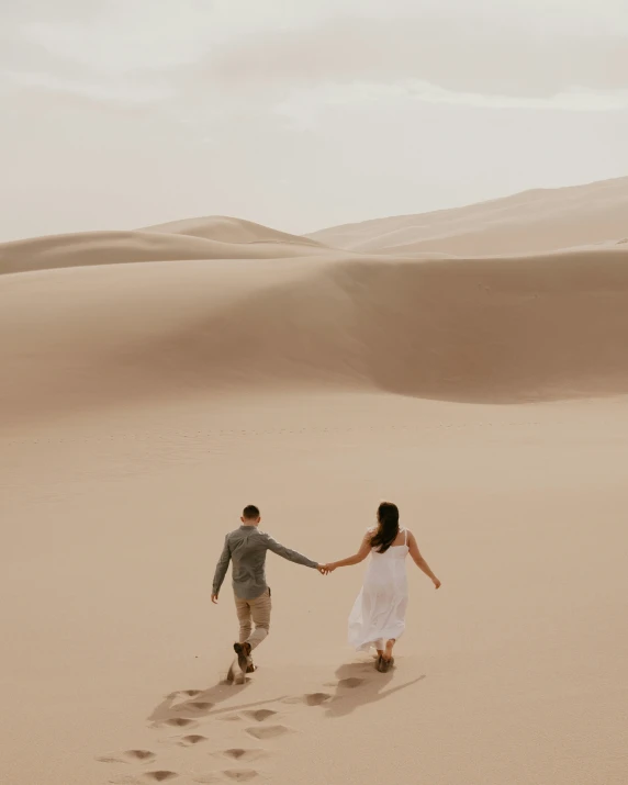 couple holding hands and walking through the desert