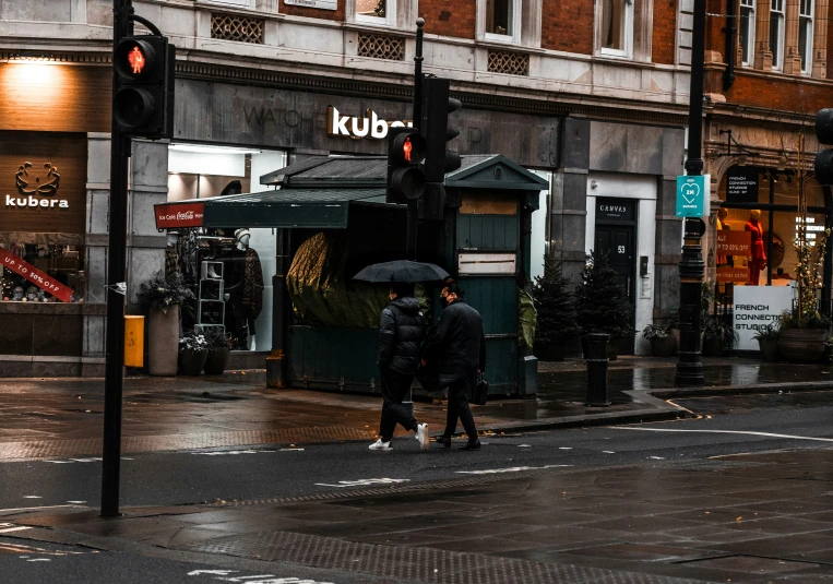 people crossing the street in the rain under an umbrella