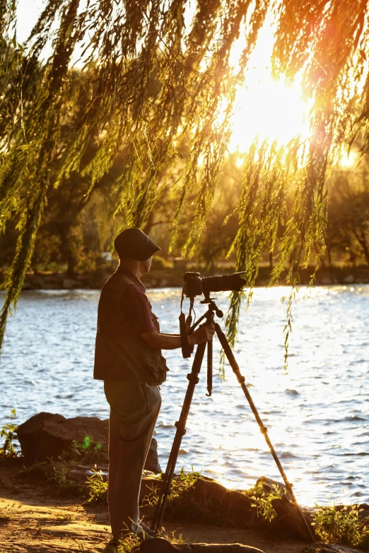 a man standing next to a tree holding a camera