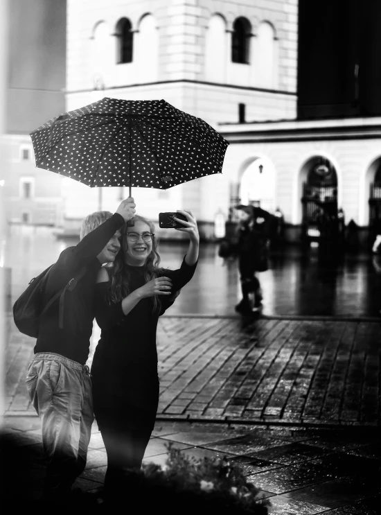 two women walking down the street under umbrellas