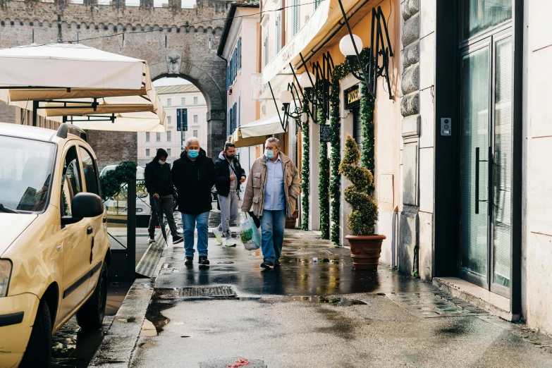 people walk down an old cobblestone street with umbrellas