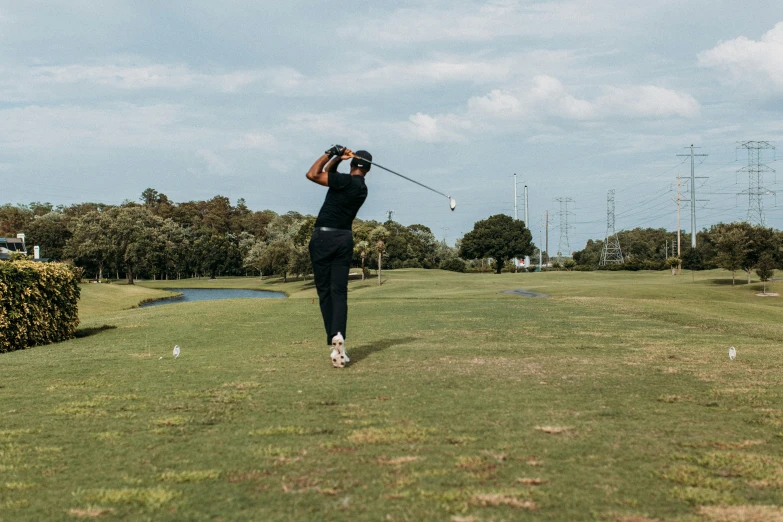 man in black shirt and cap swinging his golf club