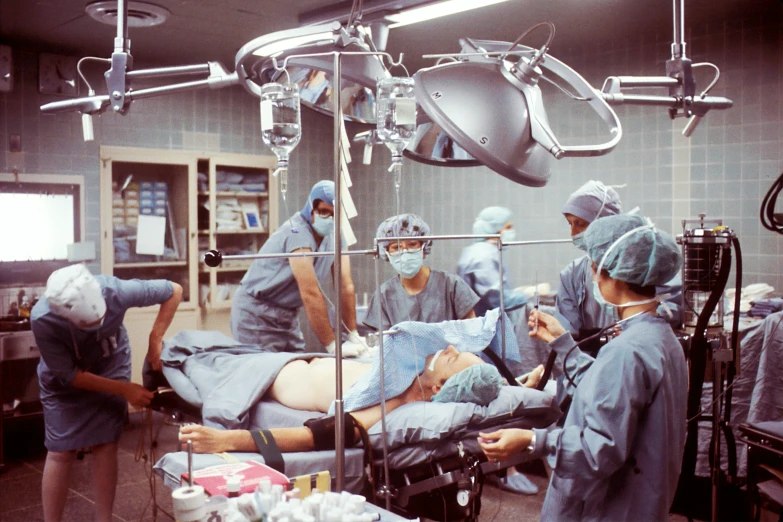 a group of doctors in scrubs and face masks operating on an infant