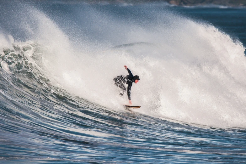 a person in a wet suit riding a wave on a surfboard