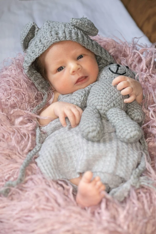 a baby sitting in the bed with a stuffed animal