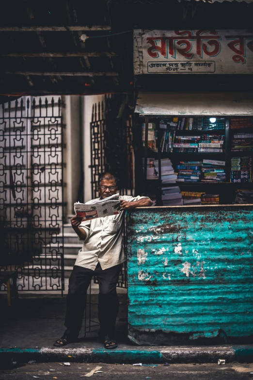 a man standing next to a building with a newspaper