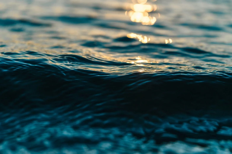 an ocean surface is blurry with the sun shining over the water