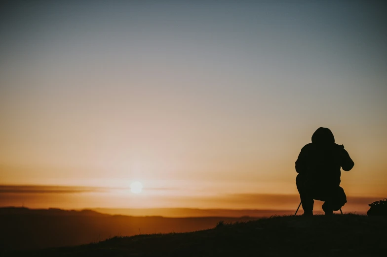 a person standing on top of a hill with the sun in the background