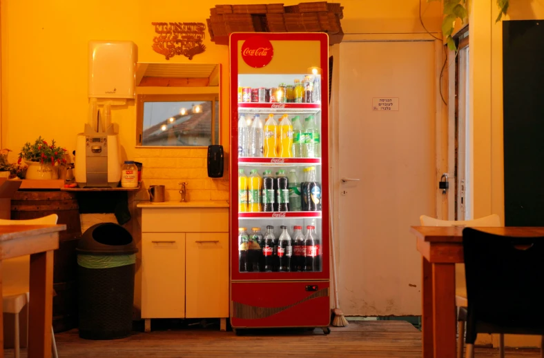 a red fridge sitting inside of a room filled with bottles of soda