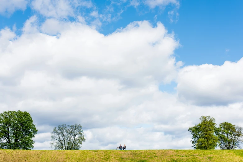 two people on a bench looking at some clouds