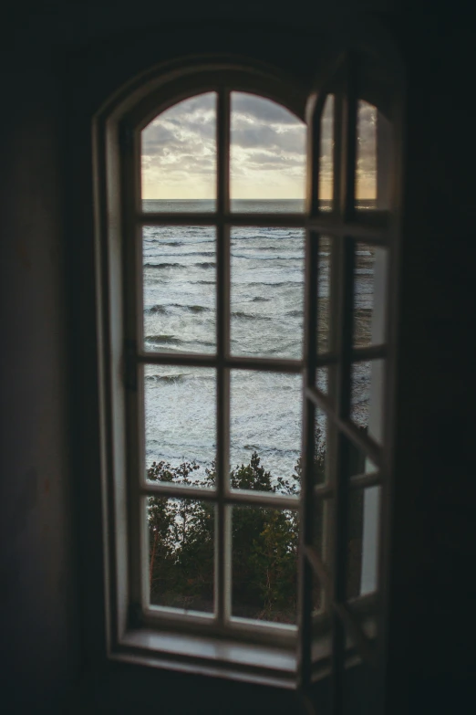 a open window shows water and beach on a cloudy day