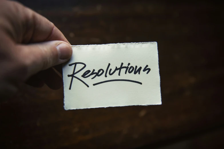 a hand holds a piece of paper that reads resolution