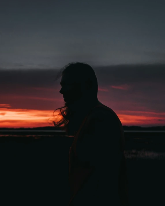 the sun is just visible in the horizon as silhouettes of a man